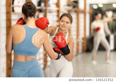 Young girl training boxing with partner during sports classes 130121352