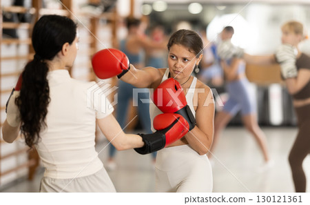 Women fight with hands, using all strength, courage during boxing lesson Women fight with hands, using all strength, courage during boxing lesson 130121361