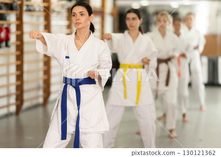 Young woman practicing punches standing in row with others 130121362
