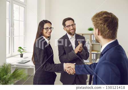 Business people standing in office making deal. Man shaking hands with woman finishing meeting. 130121418