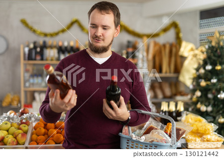 Man holding two bottles of whiskey in Christmas supermarket 130121442