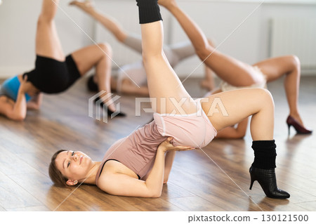 Female slender dancers in high heels and tight sexy clothes pose on floor 130121500