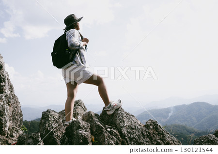 Woman hiker on top of mountain. Hiker with arms up on top of mountain successful young woman enjoying triumph. traveler exploring world. Hikers with backpacks relaxing. Sport and success concept. 130121544