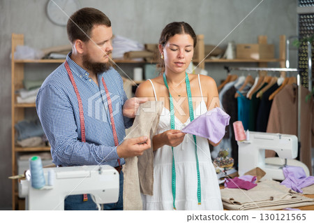 Male fashion designer reviewing fabric swatches with colleague Male fashion designer reviewing fabric swatches with colleague 130121565