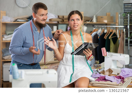 Young female dressmaker harasses male tailor 130121567