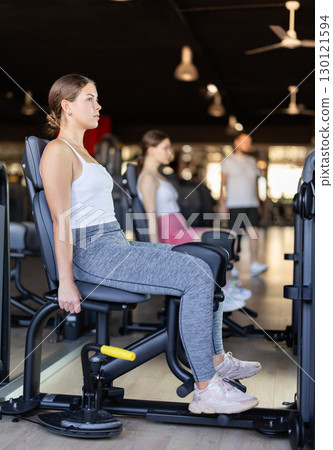 Young woman training her leg muscles on machine Young woman training her leg muscles on machine 130121594