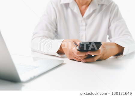 Close-up businesswoman using smart mobile phone at office table, female student is home studying online e-learning, searching for information on internet, engaging with social networks. Close-up businesswoman using smart mobile phone at office table, female student is home studying online e-learning, searching for information on internet, engaging with social networks. 130121649