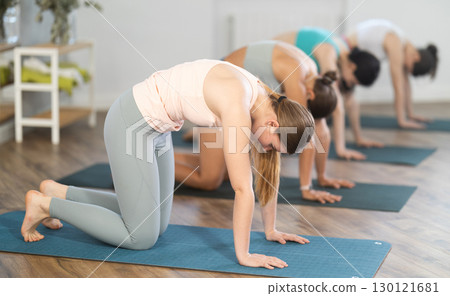 Young girl practicing Cat Cow pose at group yoga session 130121681