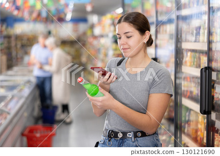 Woman purchaser scanning label of cool drink by phone Woman purchaser scanning label of cool drink by phone 130121690