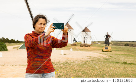 Woman tourist who came to Mota del Cuervo takes pictures of the surroundings with a mobile phone 130121693