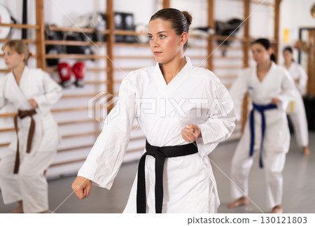 Young woman practicing kata standing in row with others 130121803
