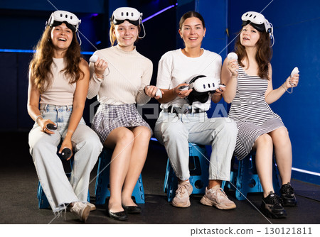 Cheerful teenage girls sitting in virtual reality game room 130121811