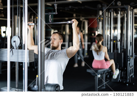 Young athletic man work out muscles of hands on cable crossover machine in fitness club Young athletic man work out muscles of hands on cable crossover machine in fitness club 130121883