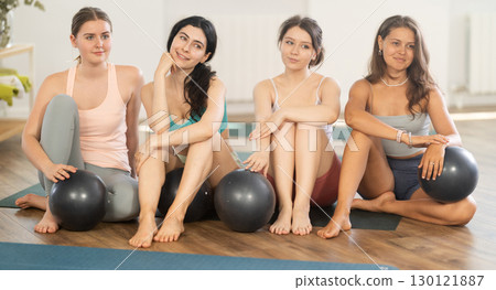 Happy portrait of young women posing with mats, going to practicing yoga at gym 130121887