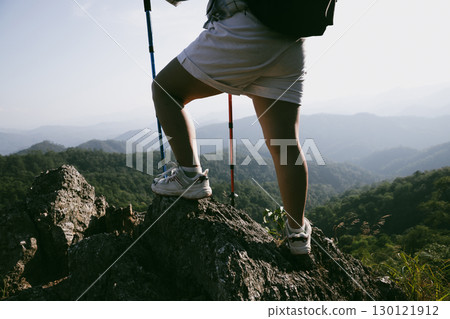 Hiking boot. Close up of female legs in boots on hiking trail on top of mountain outdoor. young woman reaching top of mountain. women feet wearing hiking boots on rock. Travel, vacation concept. 130121912