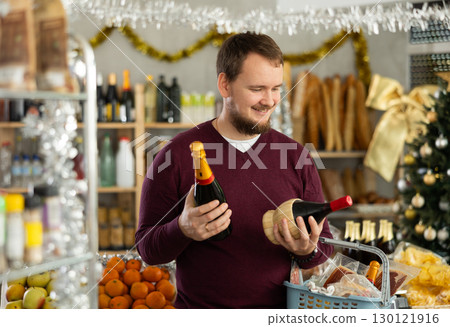 Young man picking out wine in cozy holiday store 130121916