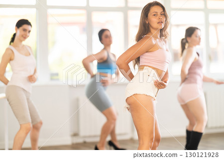 Women wearing casual activewear performing sensual and modern high heels choreography during group class in studio Women wearing casual activewear performing sensual and modern high heels choreography during group class in studio 130121928