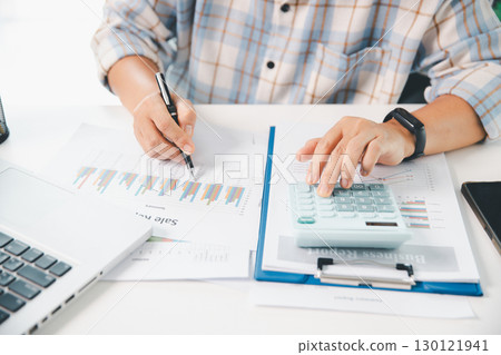 Accountant working on desk using calculator for calculate finance report in office. business finance, calculate tax by organizing financial documents, tracking income investment, accounting by hand. Accountant working on desk using calculator for calculate finance report in office. business finance, calculate tax by organizing financial documents, tracking income investment, accounting by hand. 130121941