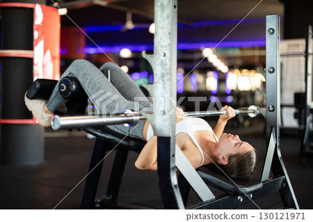 Young woman exercising on barbell machine 130121971