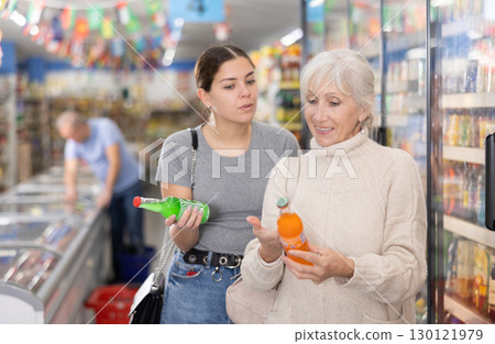 Mom with adult daughter choose and buy bottles of carbonated drink in supermarket 130121979