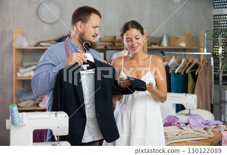 Male dressmaker showing finished jacket to young girl 130122089