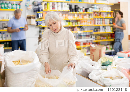 Elderly woman buying dried corn in grocery store 130122148