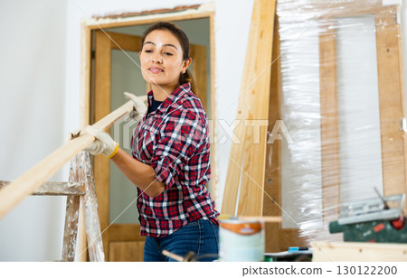 Woman doing home renovation - preparing the door for installation in doorway 130122200