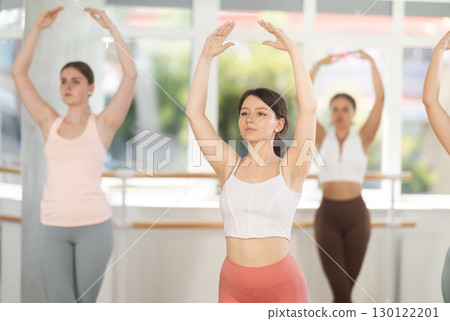 Young girl practicing basic ballet movements at group class 130122201