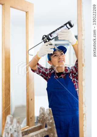 Experienced female door installer fills gaps with mounting foam 130122209