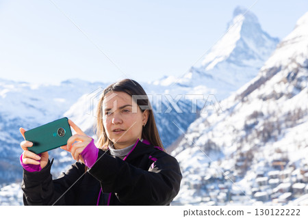 Woman travel blogger using smartphone to record vlog while hiking in Swiss Alps 130122222