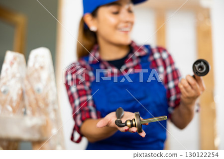 Defocused woman worker assembling door handle 130122254