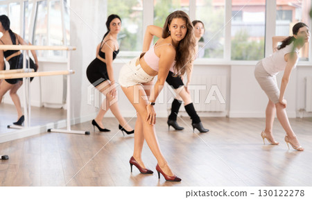 Graceful women blending sensuality with fashion while partaking in group high heels dance class 130122278