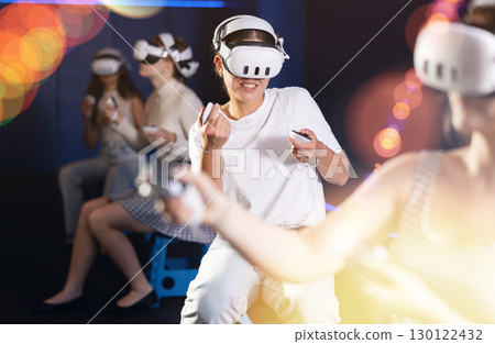 Young woman immersed in virtual reality game in gaming center 130122432