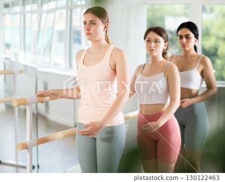 Young girl practicing first position holding by ballet barre Young girl practicing first position holding by ballet barre 130122463