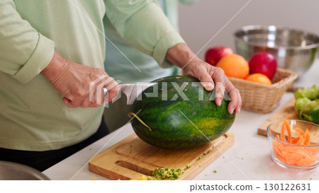 Adult hands slice fresh watermelon chopping board kitchen counter prepare healthy fruit meal home cooking wellness food prep Adult hands slice fresh watermelon chopping board kitchen counter prepare healthy fruit meal home cooking wellness food prep 130122631