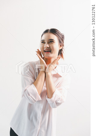 Asian woman rejoicing, looking happy, champion, fist pump gesture, standing over white background. young woman had happy, positive expression on her face, highlighted by bright smile. 130122761