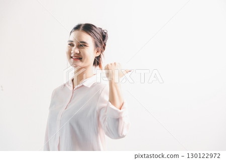 Asian woman rejoicing, looking happy, champion, fist pump gesture, standing over white background. young woman had happy, positive expression on her face, highlighted by bright smile. 130122972