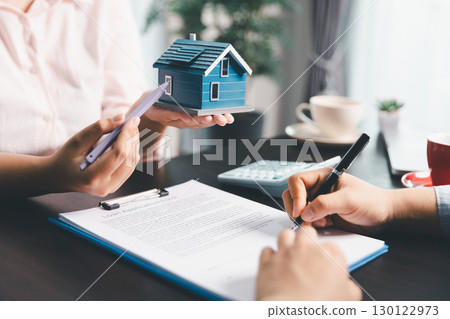 Woman real estate sale agent, client after signing agreement contract real estate with approved mortgage application form concerning mortgage loan offer, house insurance. contract agreement in office 130122973