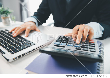 Accountant working on desk using calculator for calculate finance report in office. business finance, calculate tax by organizing financial documents, tracking income investment, accounting by hand. Accountant working on desk using calculator for calculate finance report in office. business finance, calculate tax by organizing financial documents, tracking income investment, accounting by hand. 130122992