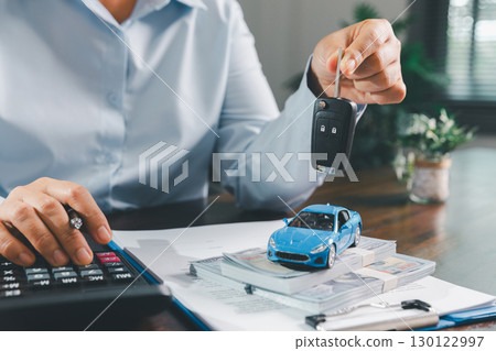 Businesswoman signing car insurance document or lease paper. Writing signature on contract or agreement. Buying or selling new or used vehicle. Car keys on table. Warranty or guarantee. Businesswoman signing car insurance document or lease paper. Writing signature on contract or agreement. Buying or selling new or used vehicle. Car keys on table. Warranty or guarantee. 130122997