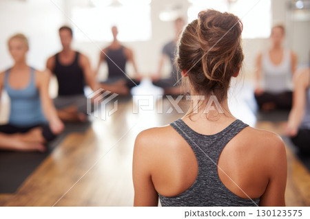 Yoga Instructor Leading Meditation Session with Participants in Studio 130123575
