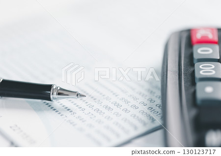 Auditor reviews financial statement and balance sheet on desk using a calculator, representing the concept of accounting, audit, and finance in preparing a detailed financial report for the business. 130123717