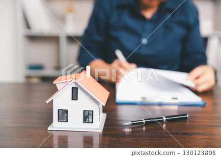 House model placed on table alongside coins, paperwork symbolizes real estate investment, property valuation, representing financial planning, mortgage options, market analysis in property business. House model placed on table alongside coins, paperwork symbolizes real estate investment, property valuation, representing financial planning, mortgage options, market analysis in property business. 130123808