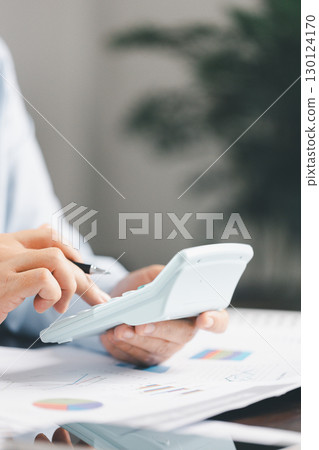 Businesswoman at table, calculator, monthly tax calculations, budgeting, managing expenses-illustrating business, finance, accounting, banking concept essential for effective budget management. Businesswoman at table, calculator, monthly tax calculations, budgeting, managing expenses-illustrating business, finance, accounting, banking concept essential for effective budget management. 130124170