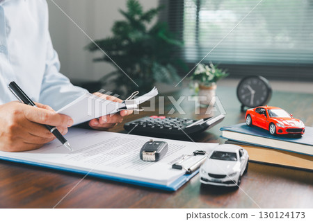 Businesswoman signing car insurance document or lease paper. Writing signature on contract or agreement. Buying or selling new or used vehicle. Car keys on table. Warranty or guarantee. Businesswoman signing car insurance document or lease paper. Writing signature on contract or agreement. Buying or selling new or used vehicle. Car keys on table. Warranty or guarantee. 130124173