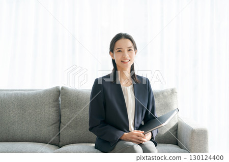 A woman in a suit sitting on a sofa 130124400