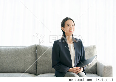 一位身著西裝的女士坐在沙發上 130124401