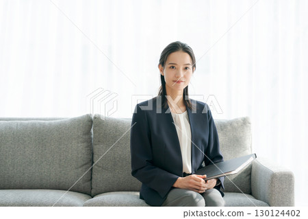 A woman in a suit sitting on a sofa A woman in a suit sitting on a sofa 130124402