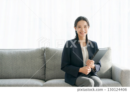 一位身著西裝的女士坐在沙發上 一位身著西裝的女士坐在沙發上 130124406