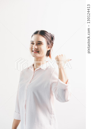 Asian woman rejoicing, looking happy, champion, fist pump gesture, standing over white background. young woman had happy, positive expression on her face, highlighted by bright smile. 130124413